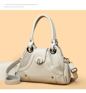 Detailed close-up of cream lychee texture leather bag with rivets and metal ring handle