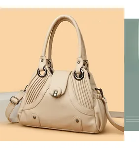 Detail of cream lychee texture handbag featuring pleated design and bronze metal rings