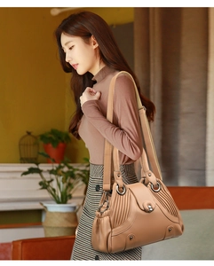 Close-up of khaki pebbled leather shoulder bag with accordion pleats and metal clasp