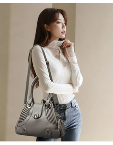 Detail of dark gray matte leather bag with accordion pleats and silver ring handle