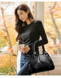 Detail of black pebbled leather handbag with side accordion pleats and silver hardware