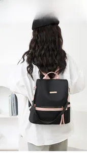 Rear view of a black waterproof nylon backpack with pink straps and leather tassel