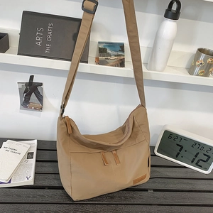 Large khaki nylon crossbody bag with dual front pockets and adjustable black strap