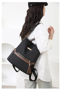 Detail of black nylon backpack with brown leather trim and tassel for women