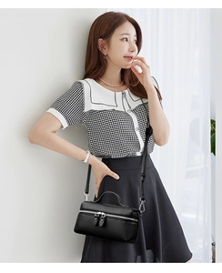 Detail of black lychee grain leather handbag with silver zipper and top handle
