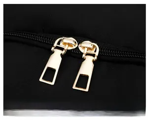Detail of durable nylon fabric with premium gold double zippers on a black backpack