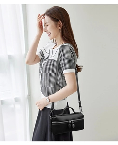 Detail of black pebbled leather box bag with silver zippers and elegant crossbody strap