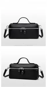 Detail view of black lychee grain leather handbag with dual zippers and crossbody strap