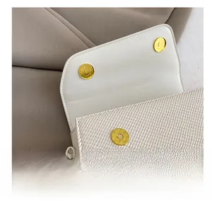 Détail du fermoir magnétique doré et de la texture tissée d'un petit sac blanc élégant