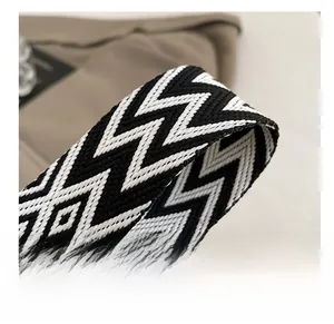 Détail d'une large bandoulière tissée aux motifs géométriques noirs et blancs