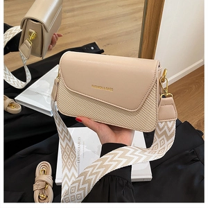 Détail du sac beige texturé avec large bandoulière géométrique et boucles dorées