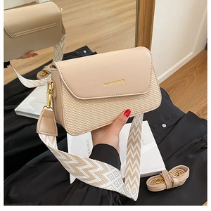 Détail du sac bandoulière beige en cuir et paille avec large sangle tissée géométrique