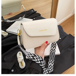 Détail du sac bandoulière beige avec texture tissée et large sangle à motif géométrique