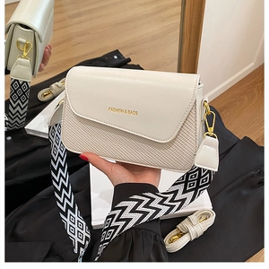 Détail du sac bandoulière crème avec texture tissée et large bandoulière géométrique