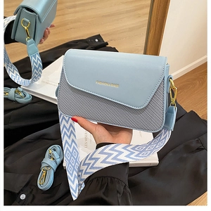Sac bandoulière bleu clair montrant les deux sangles et le texte sur le rabat en cuir