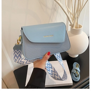 Détail du sac bandoulière bleu clair avec texture tissée et large sangle tendance