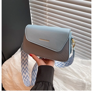 Détail d'un sac bandoulière bleu clair avec texture tressée et large sangle géométrique
