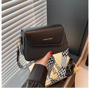 Détail du sac bandoulière noir avec large sangle géométrique tissée et lanière en cuir