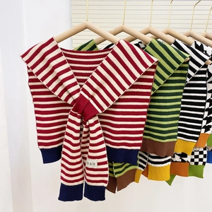 Scialle in maglia a righe con lacci decorativi frontali ed etichetta geometrica