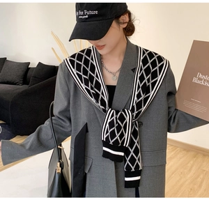 Detail of black and white checkered knit shawl styled over a gray blazer for women