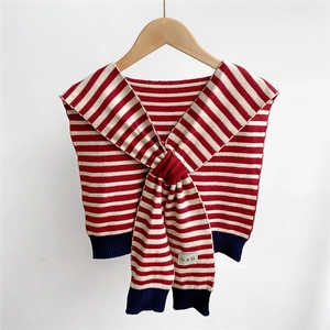Dettaglio di scialle in maglia a righe bianche e rosse con bordi blu navy ed etichetta