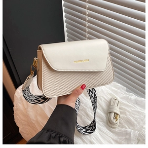 Détail du sac bandoulière crème avec texture tressée et large sangle à motifs tendance