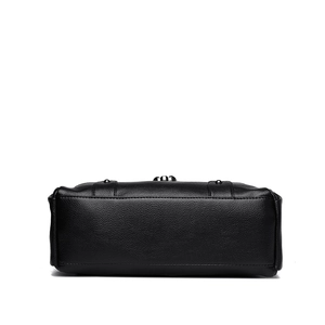 Bottom view of black pebble leather underarm bag featuring protective metal studs and stitching