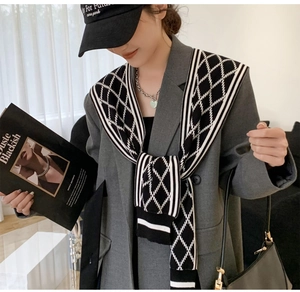 Close-up of houndstooth knit shawl styled over a grey blazer with chic urban accessories