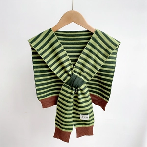 Dettaglio di uno scialle in maglia a righe con patch geometrica su gruccia in legno