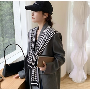 Detail of a knitted black and white houndstooth shawl draped over a gray coat for women