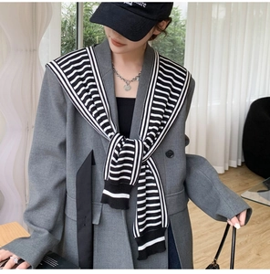 Detail of black and white striped knit shawl layered over a dark grey blazer