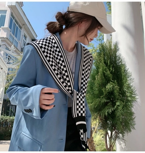 Chic black and white checkered knit shawl styled over a light blue blazer jacket detail