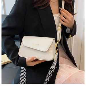 Détail d'un sac à bandoulière blanc en cuir mat avec large sangle et texture tressée