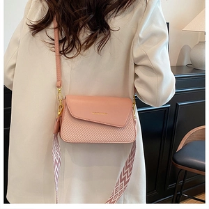 Détail du sac bandoulière rose avec sangle en tissu texturé et logo imprimé tendance