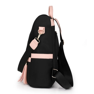 Black nylon backpack with pink leather trim and side tassel detail, 45-degree side view