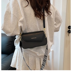 Détail d'un sac bandoulière noir avec texture tressée et large sangle