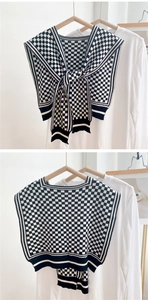 Detail of black and white checkered knitted shawl wrap with elegant front tie design
