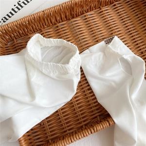 Close-up of white sun protection sleeves with thumb holes in a rustic woven basket