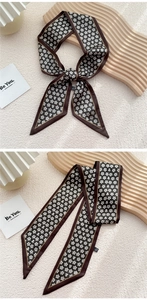 Vue détaillée d'un foulard twilly marron à fleurs noué en boucle sur un plateau en bois