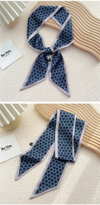 Détail d'un foulard en satin bleu marine à motif trèfle noir et bordure bleu clair
