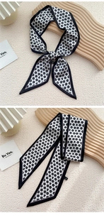 Gros plan du foulard étroit en soie avec motif trèfle noir noué en nœud élégant