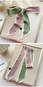 Détail d'un foulard étroit vert olive et rose poudré avec liseré blanc et logo discret