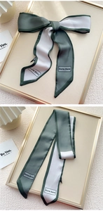 Détail d'un foulard en soie vert foncé et beige avec nœud et imprimé logo élégant
