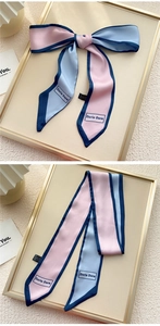 Détail d'un foulard en satin rose et bleu noué en nœud avec lettrage de marque élégant