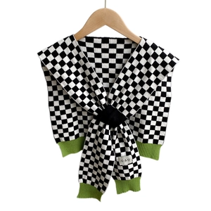 Scialle in maglia a scacchi con bordo a coste verde e motivi geometrici su sfondo bianco