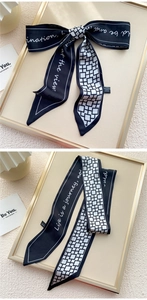 Détail d'un foulard twilly en soie noir et blanc avec écriture française et motifs