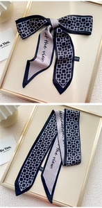 Détail du foulard twilly double face avec motif géométrique et texte cursif