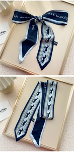 Détail d'un foulard twilly en satin bleu marine avec imprimés chevaux et texte positif