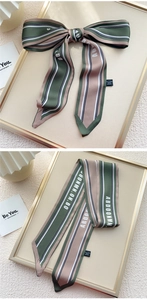 Détail d'un foulard étroit en soie à rayures vertes et imprimé lettres pour la coiffure