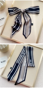 Détail d'un foulard en soie 100% avec motif de lettres rayées noires et blanches